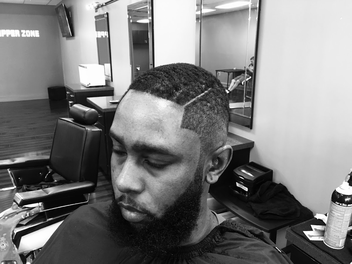 Inside Clipper Zone — barber chair, mirrors and the studio wall sign
